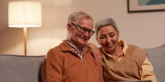 Man And Woman On Sofa Looking At Laptop