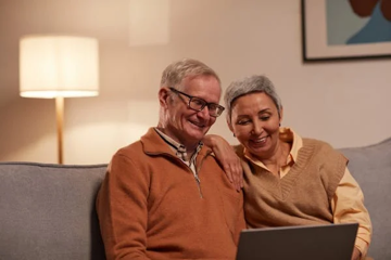 Man And Woman On Sofa Looking At Laptop