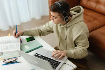 Teenager On Laptop And Writing